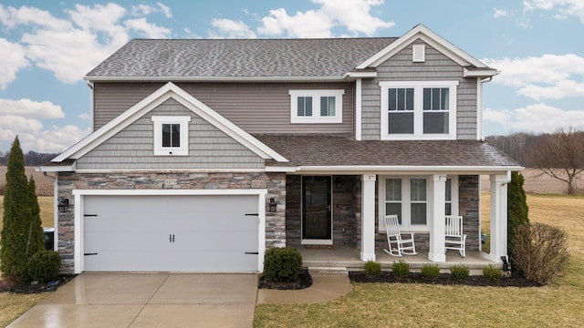 craftsman inspired home with driveway, a front yard, stone siding, a shingled roof, and a porch