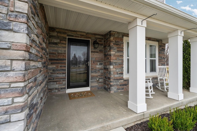 entrance to property with covered porch and stone siding