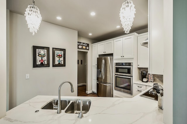 2667 Oxford Cir, Ann Arbor, MI 48103 - kitchen with stainless steel appliances, a chandelier, a sink, recessed lighting, and white cabinetry