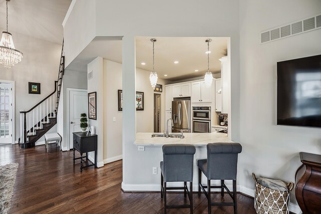 2667 Oxford Cir, Ann Arbor, MI 48103 - kitchen featuring appliances with stainless steel finishes, a sink, baseboards, white cabinetry, and a towering ceiling