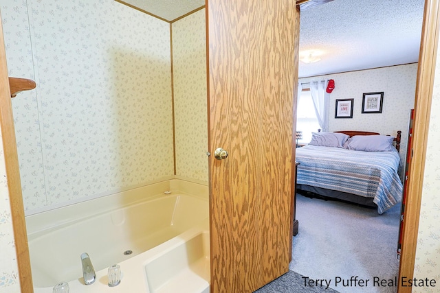 full bathroom with ensuite bathroom, a textured ceiling, wallpapered walls, and a jetted tub