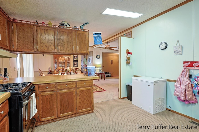 kitchen featuring a textured ceiling, fridge, gas stove, and brown cabinets