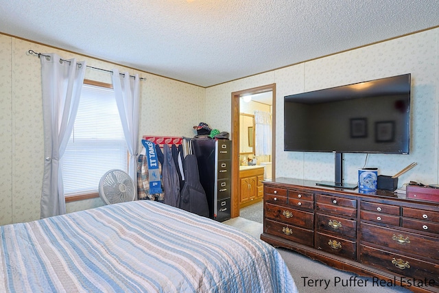 bedroom featuring wallpapered walls, ensuite bathroom, light colored carpet, and a textured ceiling