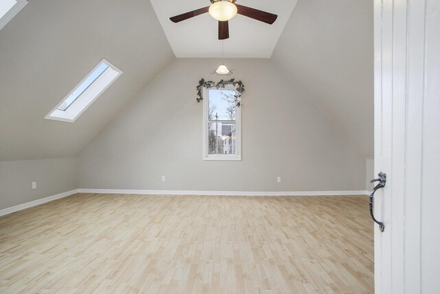 bonus room with baseboards, wood finished floors, lofted ceiling with skylight, and a ceiling fan