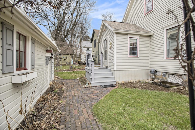 view of property exterior with a lawn and roof with shingles