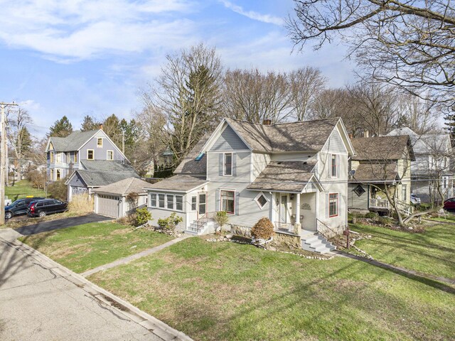 view of front facade featuring a garage, a front yard, aphalt driveway, and a chimney