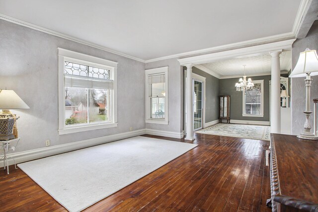 entryway with ornate columns, ornamental molding, baseboards, hardwood / wood-style flooring, and a notable chandelier
