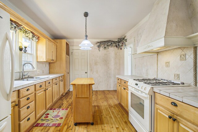 kitchen with white appliances, tile countertops, a sink, and premium range hood