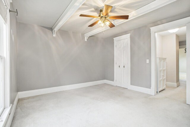 unfurnished room with a ceiling fan, light carpet, baseboards, and beamed ceiling