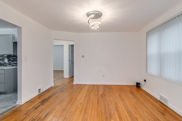 11135 Courville St, Detroit, MI 48224 - spare room with visible vents, light wood-style flooring, and a chandelier