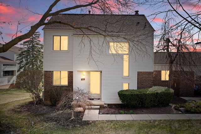 view of front of house featuring brick siding and roof with shingles