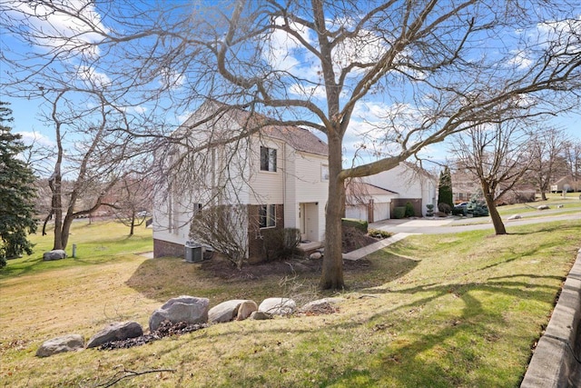 view of side of home with central AC, a lawn, a garage, and driveway