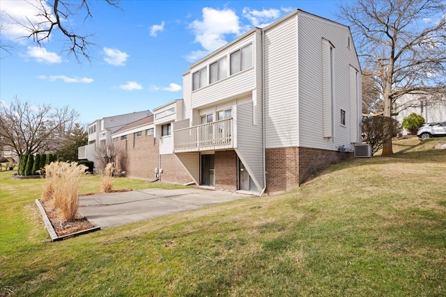 rear view of house with brick siding, a lawn, central air condition unit, and a residential view
