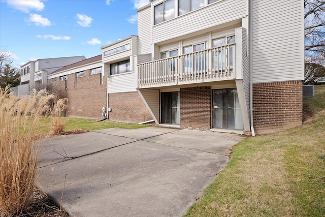back of house with brick siding, a patio, central AC, and a lawn