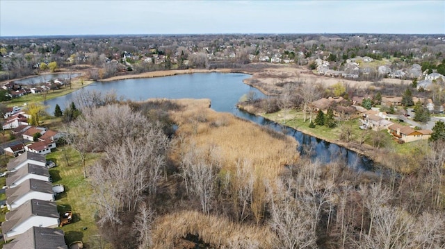 aerial view of property and surrounding area featuring a large body of water, nearby suburban area, and a tree filled landscape