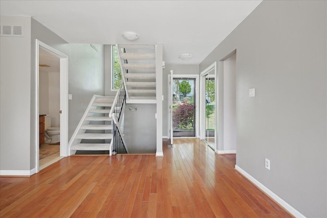 entryway with light wood-type flooring, stairway, and baseboards