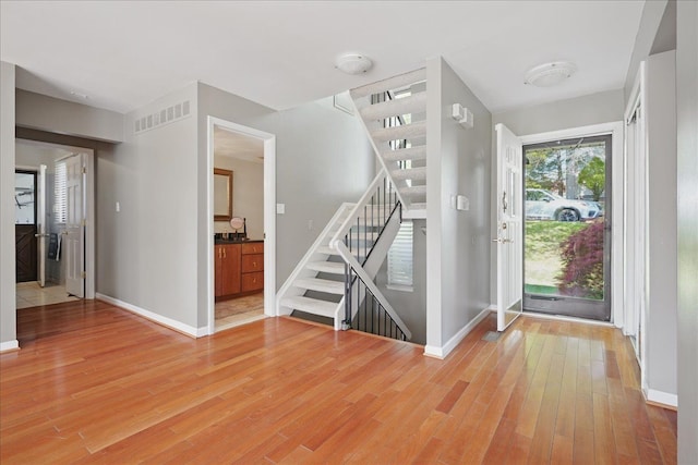 entryway with stairs, light wood-type flooring, and baseboards