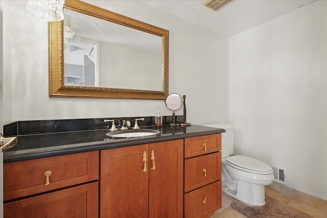 half bathroom featuring toilet, vanity, and tile patterned floors