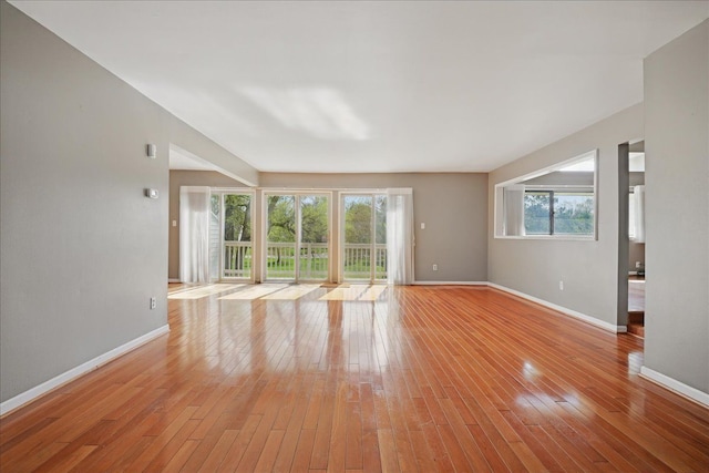 unfurnished living room with baseboards, healthy amount of natural light, and light wood-type flooring