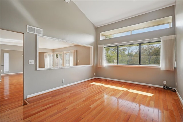 unfurnished room featuring wood-type flooring, high vaulted ceiling, and baseboards