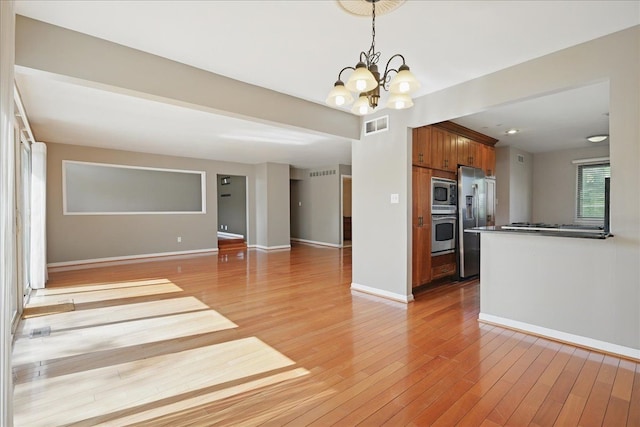 unfurnished living room featuring a chandelier, light wood finished floors, baseboards, and recessed lighting