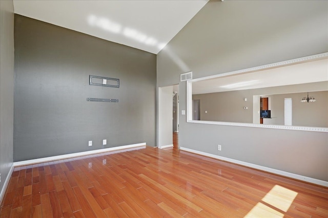 spare room with wood finished floors, baseboards, and a high ceiling