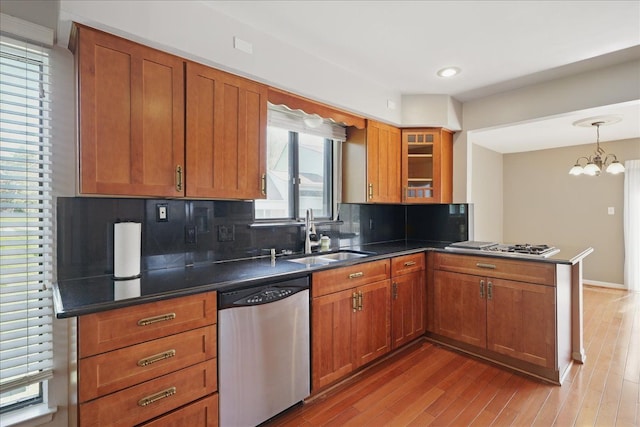 kitchen with stainless steel appliances, a sink, dark countertops, brown cabinets, and recessed lighting