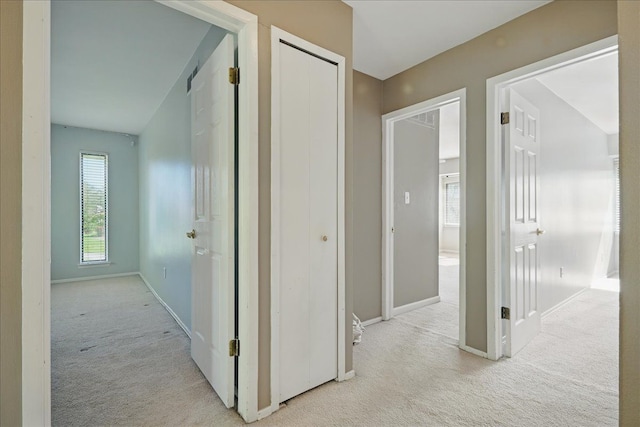 hall with light colored carpet and baseboards