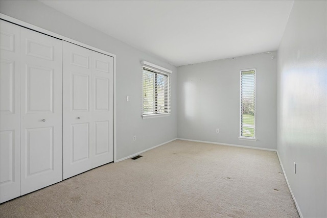unfurnished bedroom with carpet, a closet, and baseboards