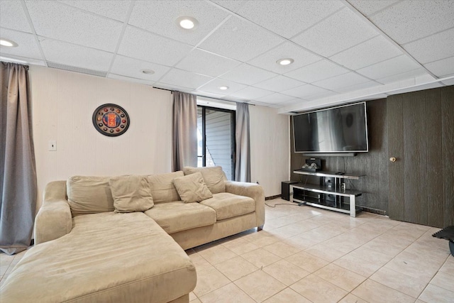 living room with a drop ceiling, light tile patterned flooring, recessed lighting, and wood walls