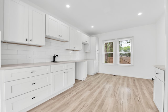 2916 Gladstone St, Detroit, MI 48206 - kitchen featuring light countertops, a sink, white cabinetry, tasteful backsplash, and light wood-type flooring