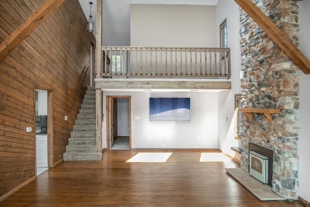 24199 N Shore Dr, Edwardsburg, MI 49112 - unfurnished living room featuring stairway, baseboards, a high ceiling, wooden walls, and wood finished floors
