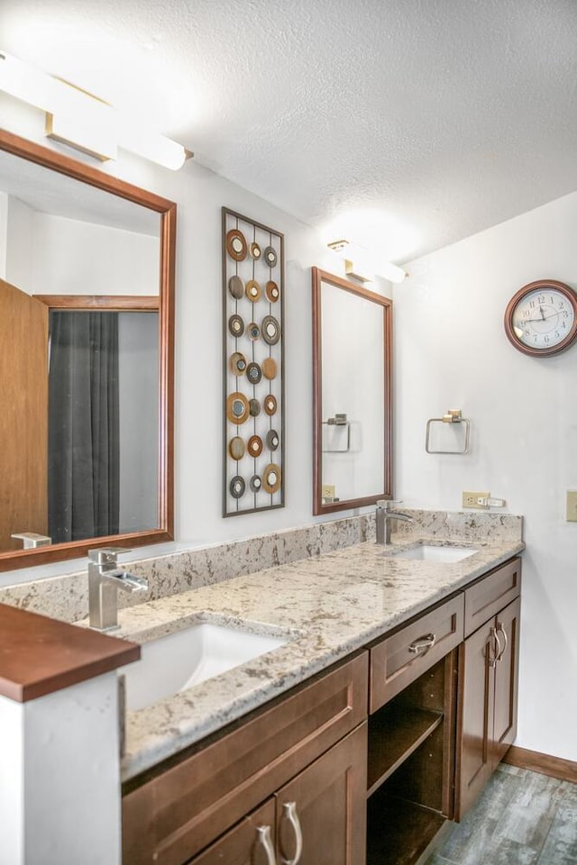 24199 N Shore Dr, Edwardsburg, MI 49112 - bathroom with double vanity, a sink, wood finished floors, and a textured ceiling