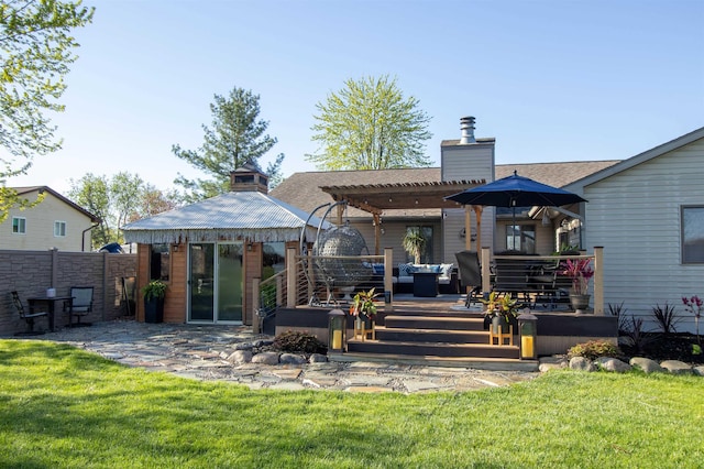 rear view of property with a chimney, an outdoor living space, a wooden deck, a pergola, and an outbuilding