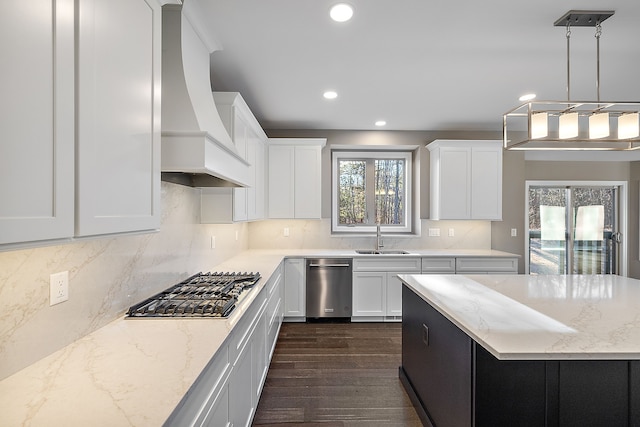 kitchen with light stone counters, a sink, white cabinetry, stainless steel gas stovetop, and custom range hood