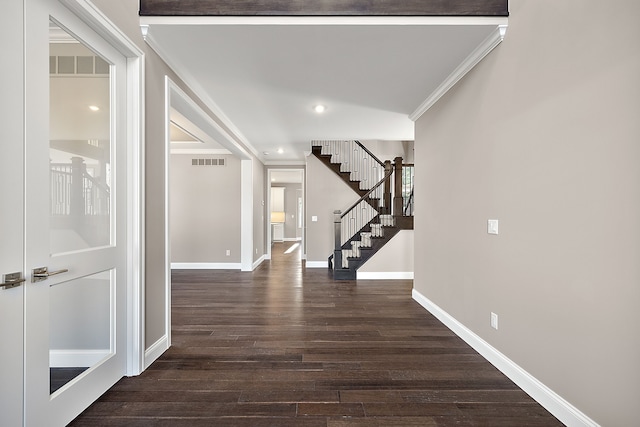 hallway featuring stairway, wood finished floors, baseboards, visible vents, and ornamental molding