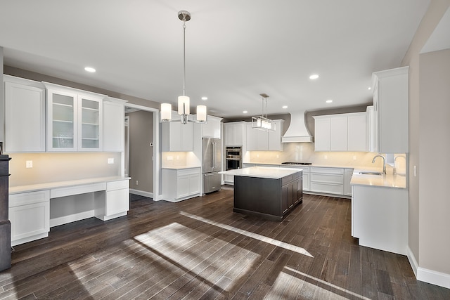 kitchen featuring light countertops, a sink, white cabinets, appliances with stainless steel finishes, and custom exhaust hood