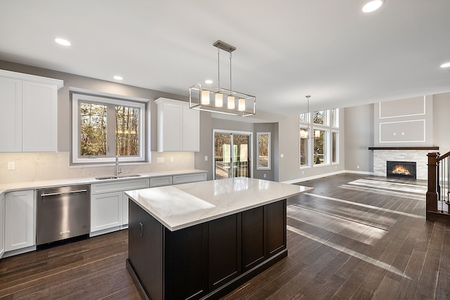 kitchen with a center island, dark wood-type flooring, white cabinetry, a sink, and stainless steel dishwasher