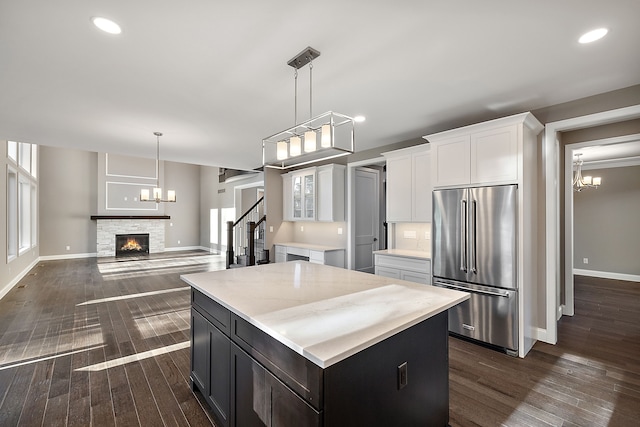 kitchen with dark wood-style flooring, high quality fridge, white cabinets, and a kitchen island
