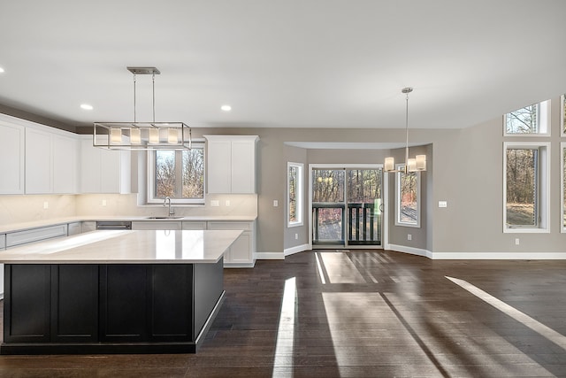 kitchen featuring dark wood-style flooring, light countertops, baseboards, a sink, and a notable chandelier
