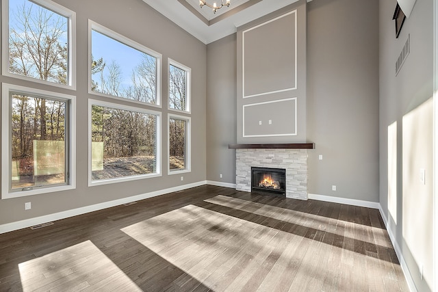 unfurnished living room with plenty of natural light, baseboards, visible vents, and a towering ceiling