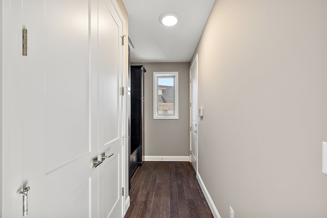 hallway featuring baseboards and dark wood-type flooring