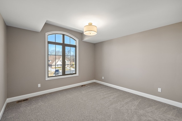 carpeted empty room featuring baseboards and visible vents
