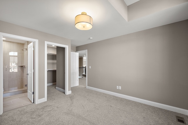 unfurnished bedroom featuring baseboards, connected bathroom, visible vents, light carpet, and a closet