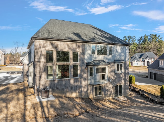 back of house featuring brick siding and central AC unit