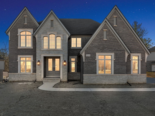 view of front facade with stone siding, brick siding, and french doors