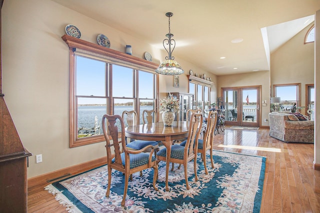 dining room featuring baseboards, visible vents, a water view, and wood-type flooring