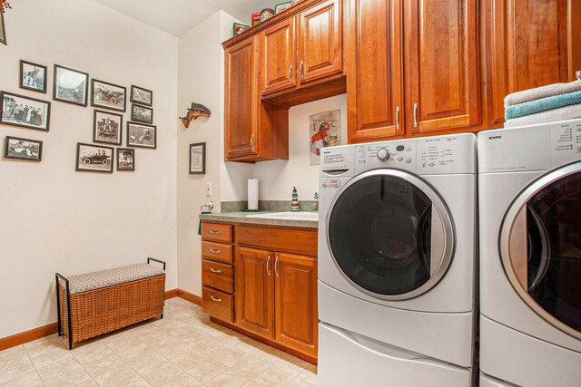 clothes washing area with baseboards, washing machine and dryer, cabinet space, and a sink