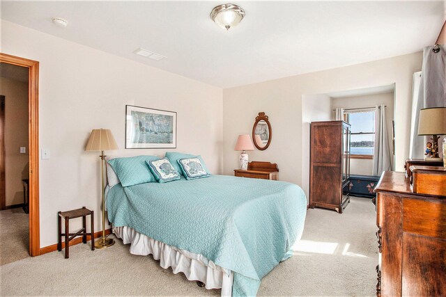 bedroom with baseboards, visible vents, and light carpet