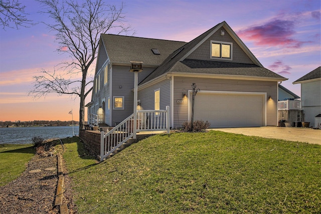 view of front of property featuring a water view, a front yard, driveway, and a shingled roof